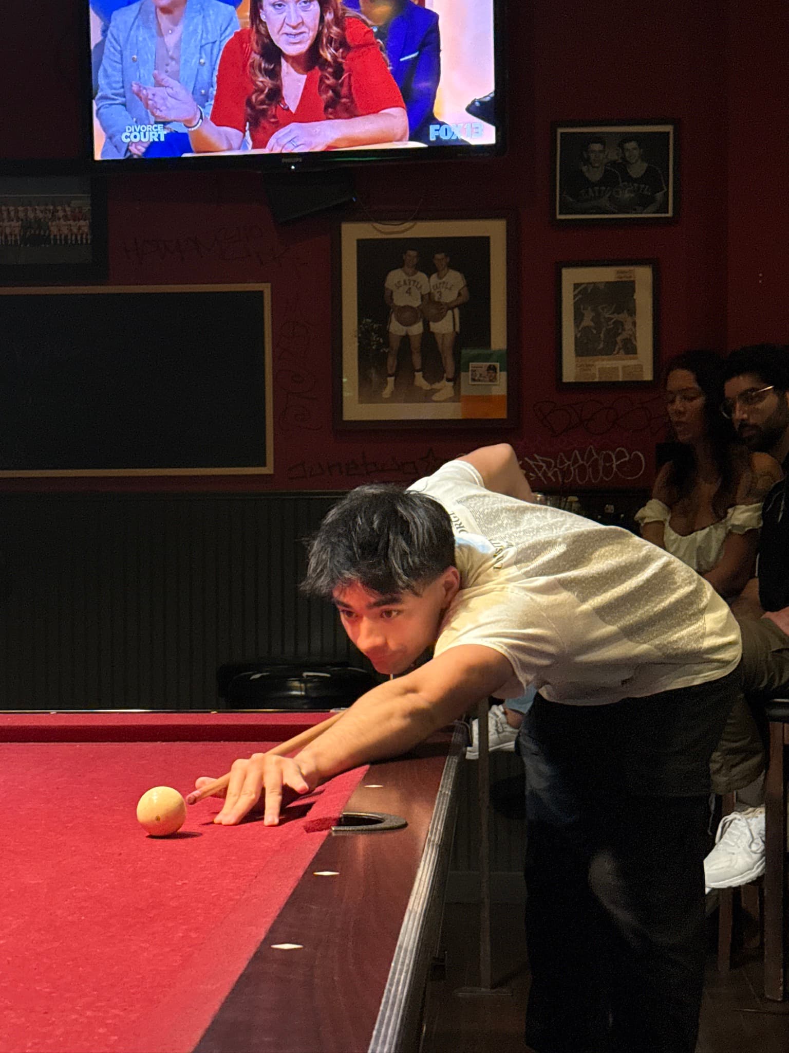 Liam lining up a shot at a pool hall